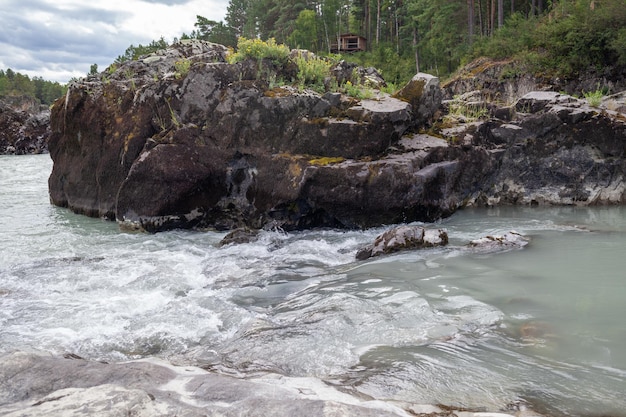 Un río de montaña ancho y caudaloso que fluye rápido. Grandes rocas sobresalen del agua.