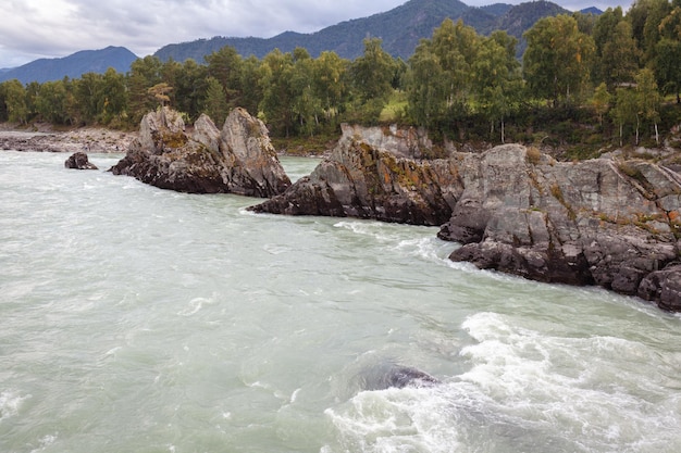 Un río de montaña ancho y caudaloso que fluye rápido. Grandes rocas sobresalen del agua.