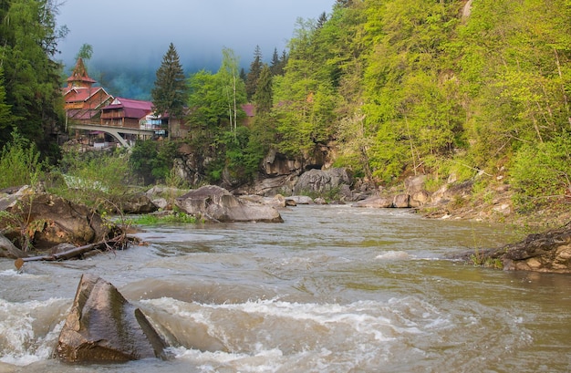 Un río en las montañas con una casa al fondo.