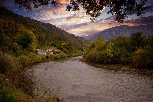 Rio nas montanhas e casas de aldeia na costa ao pôr do sol