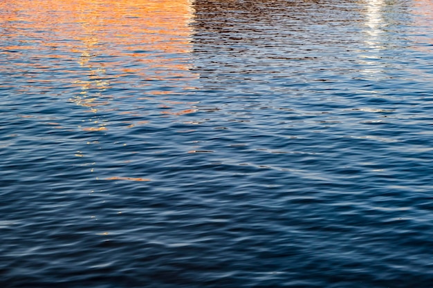 Foto río oscuro que refleja los edificios de la ciudad temprano en la mañana soleada textura del agua