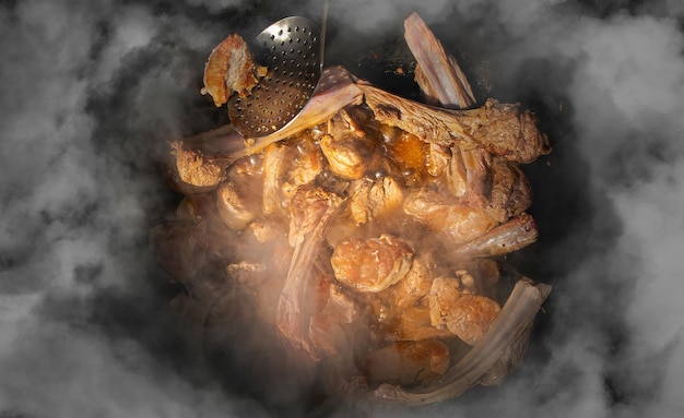 Rippen und Fleischstücke in einem Bottich werden in Dampfstößen für Pilaw gekocht