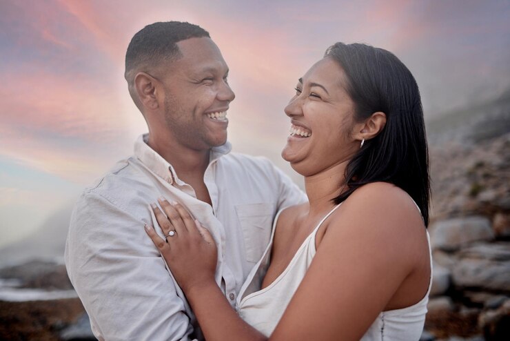 Foto rir amor e casal na praia ao pôr do sol em data romântica para viajar com férias ou viagem de fim de semana feliz ligação e jovem homem e mulher com conexão pelo oceano à noite em férias tropicais