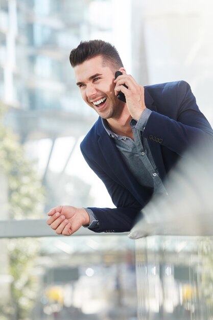 Rir o homem de negócios bem sucedido na chamada de telemóvel