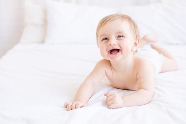 Rir ou sorrir bebê menino loiro com olhos grandes closeup ou retrato em um berço em casa o conceito de produtos e acessórios infantis