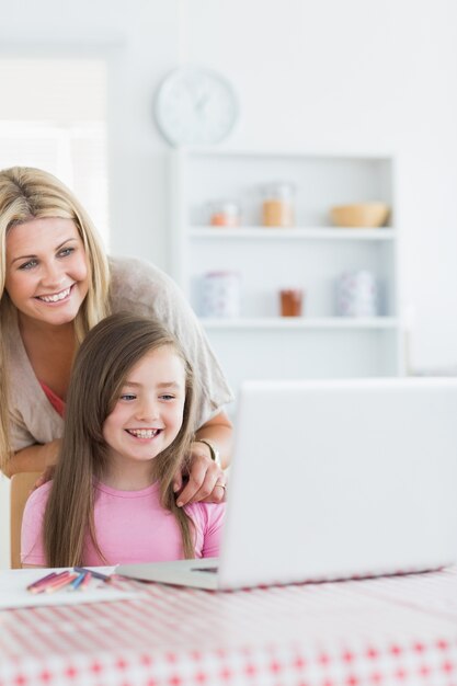 Risa de madre y niña mirando portátil