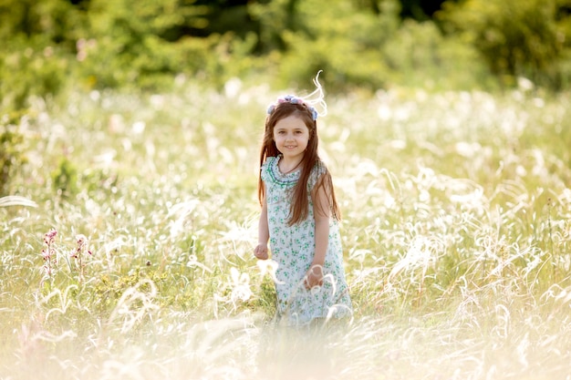 Risos felizes da menina atravessa o campo no verão