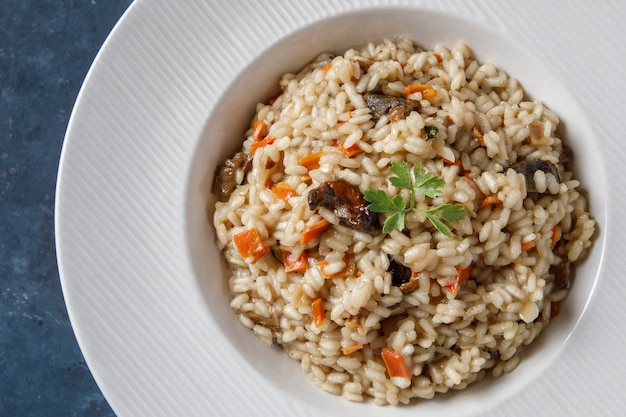 Risoto, arroz italiano com cogumelos, legumes e salsa servido em prato de porcelana branca