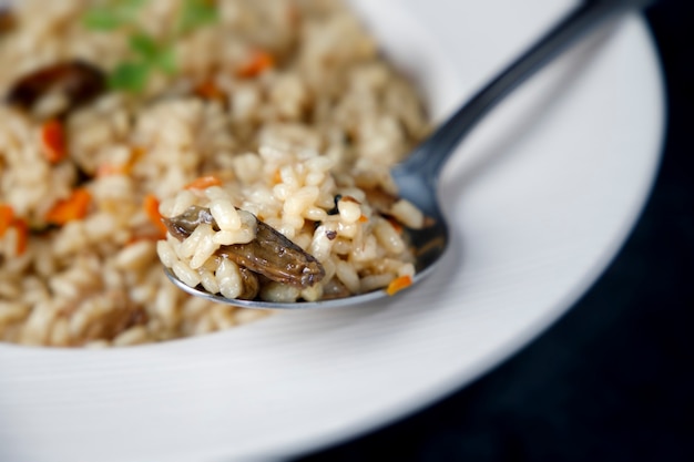 Risoto, arroz italiano com cogumelos, legumes e salsa servido em prato de porcelana branca