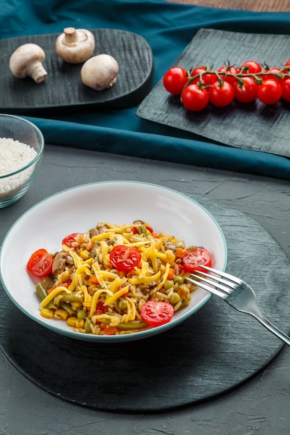 Risoto com bifes e queijo em um prato sobre uma superfície cinza em um quadro preto perto dos ingredientes