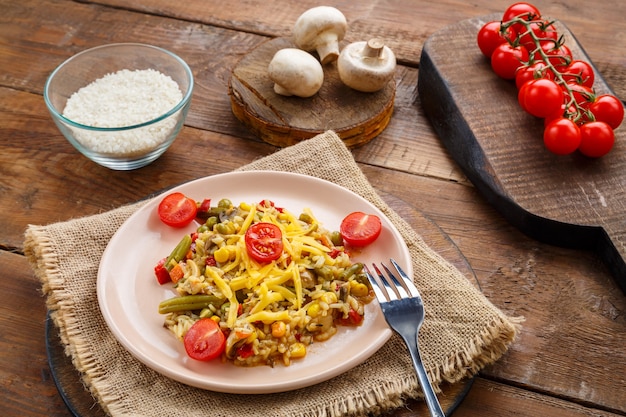 Risoto com cogumelos e queijo em um prato sobre um fundo de madeira em um guardanapo perto dos ingredientes. foto horizontal