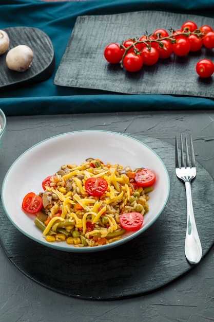 Risoto com cogumelos em um prato sobre um fundo cinza perto dos ingredientes em porta-copos pretos. Foto vertical