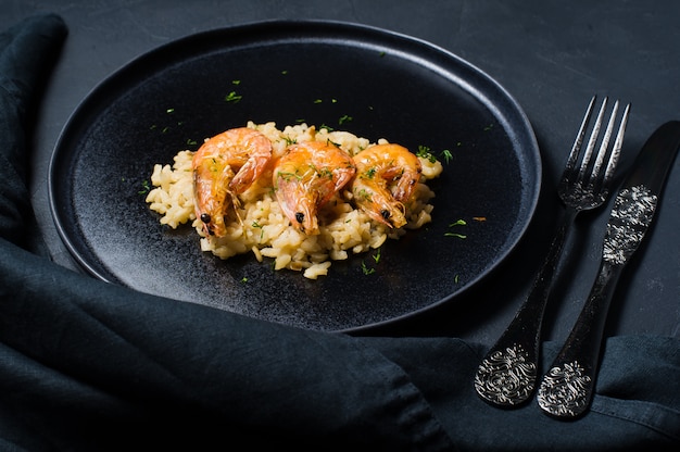 Risoto italiano com camarão em uma placa preta.