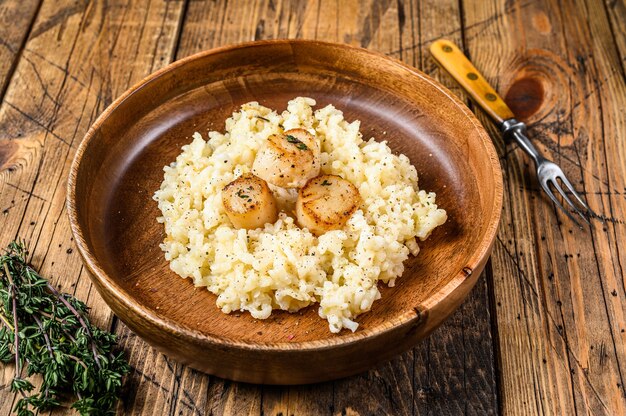 Risoto italiano com vieiras em uma panela. fundo de madeira. vista do topo.