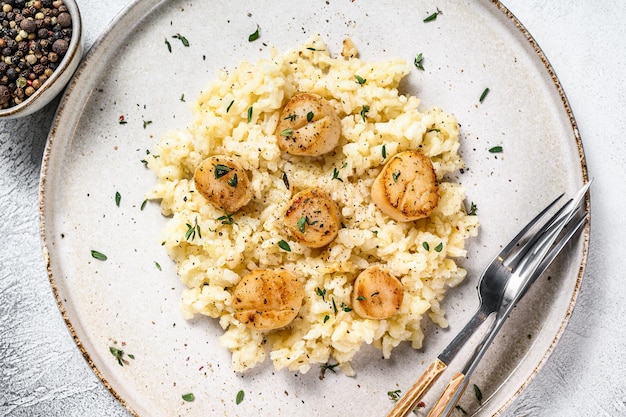 Risoto italiano com vieiras tostadas na frigideira. fundo branco. vista do topo.