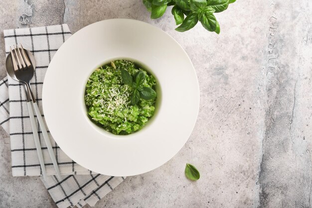 Risoto italiano Delicioso risoto em chapa branca com molho pesto ou alho selvagem pesto manjericão queijo parmesão e copo de vinho branco no antigo fundo da mesa cinza claro Vista superior com espaço de cópia