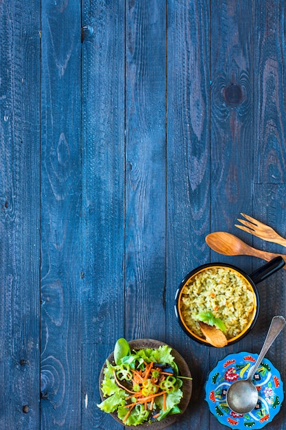 Foto risoto vegetariano com vários vegetais, na mesa rústica de madeira.