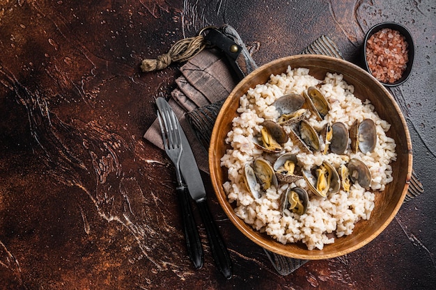 Risotto con almejas y mariscos en un plato de madera Fondo oscuro Vista superior Espacio de copia