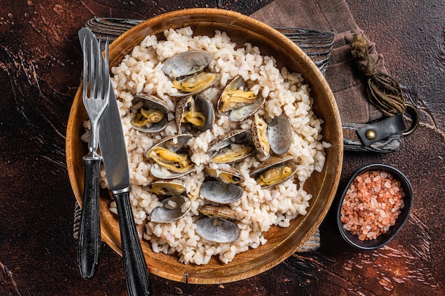 Risotto con almejas y mariscos en un plato de madera Fondo oscuro Vista superior