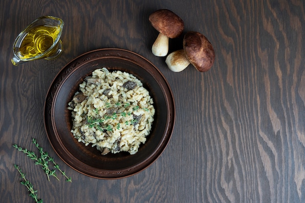 Risotto con arroz arborio, caldo, champiñones y tomillo sobre mesa de madera marrón oscuro