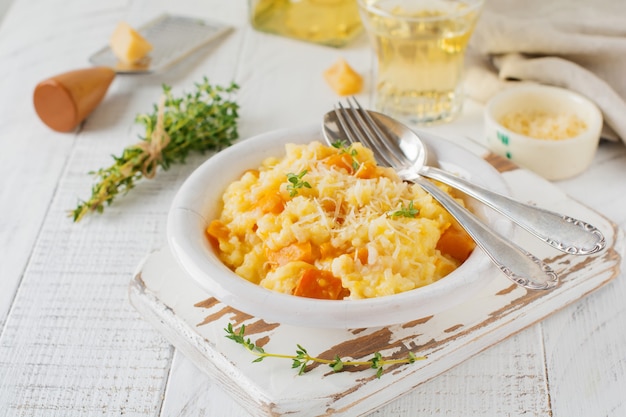 Risotto de calabaza con tomillo, ajo, queso parmesano y vino blanco sobre fondo de madera clara Estilo rústico