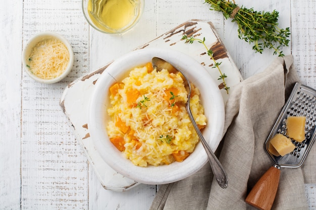 Risotto de calabaza con tomillo, ajo, queso parmesano y vino blanco sobre superficie de madera clara