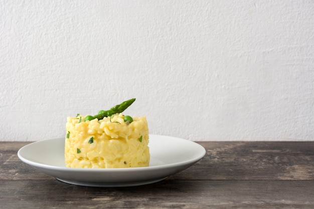 Risotto con guisantes espárragos y perejil en mesa de madera