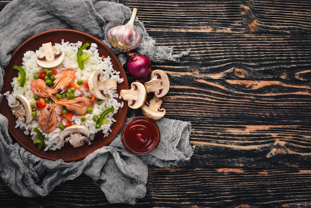 Risotto mit Garnelen und Gemüse Asiatische Küche mit Meeresfrüchten Auf einem hölzernen Texturhintergrund Ansicht von oben Freier Speicherplatz