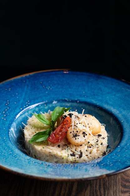 Risotto mit Jakobsmuscheln auf einem blauen Teller mit Parmesan