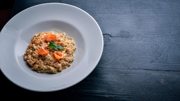 Risotto mit Lachs und Sahnesauce Auf einem hölzernen Hintergrund Ansicht von oben Freier Speicherplatz