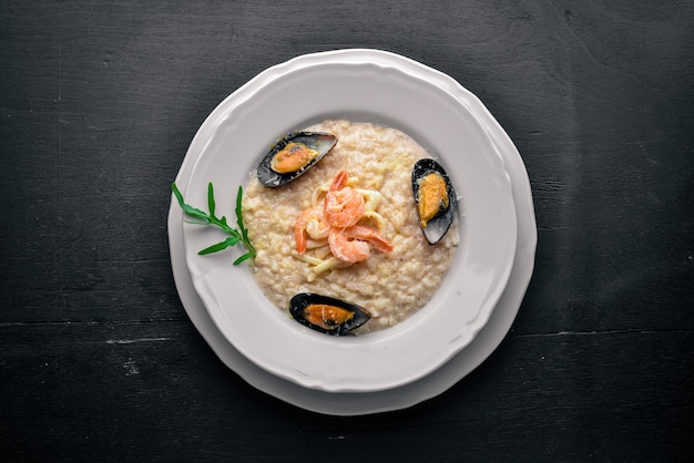 Risotto mit Meeresfrüchten, Garnelen, Muscheln und Tintenfischen und Käse Auf einem hölzernen Hintergrund Ansicht von oben Freier Speicherplatz