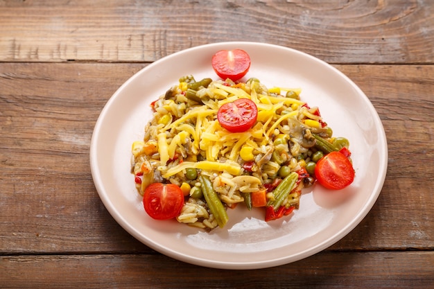 Risotto mit Pilzen und Gemüse in einem Teller auf einem hölzernen Hintergrund.