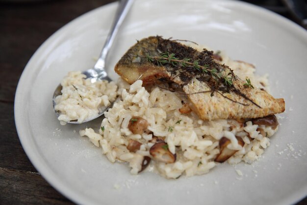 Risotto mit Wolfsbarsch-Filetsteak auf Holzhintergrund, italienisches Essen