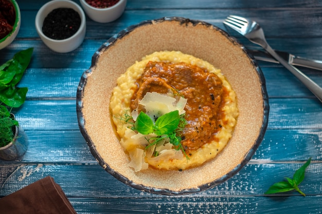 Risotto con osso buco en un plato sobre una tabla de madera azul