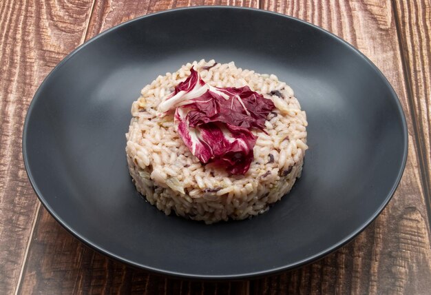 Risotto con radicchio rojo en un plato negro de la cocina italiana