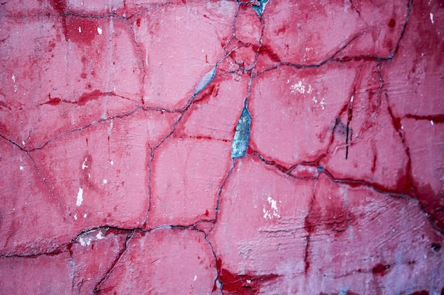 Risse auf einer rosa Wand in Nahaufnahme