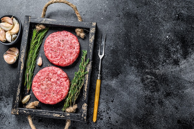 Rissóis de carne bovina crua para hambúrguer de carne moída e ervas em uma placa de madeira