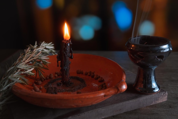 Foto ritual tradicional com fogo e vela preta em prato de barro acompanhado de pimenta ervas de sal marinho