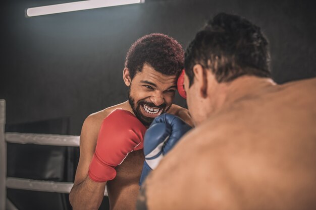 Rivalidad. Dos kickboxers peleando en un ring de boxeo y luciendo agresivos