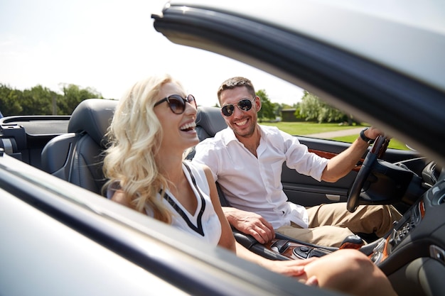 road trip, reise, dating, paar und personenkonzept - glücklicher mann und frau, die draußen im cabrioletauto fahren