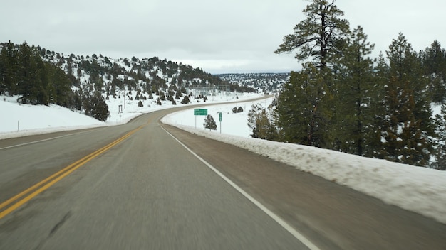 Road trip en usa desde zion to bryce canyon conduciendo auto en utah haciendo autostop viajando en américa ruta al bosque dixie invierno viaje local atmósfera tranquila y vista de montañas nevadas desde el auto