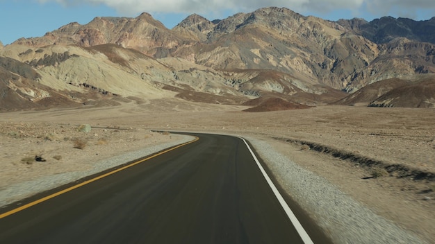 Roadtrip ins Death Valley, Artists Palette Drive, Kalifornien USA. Per Anhalter fahrendes Auto in Amerika. Autobahn, bunte kahlen Berge und trockene Klimawildnis. Blick aus dem Auto. Reise nach Nevada.