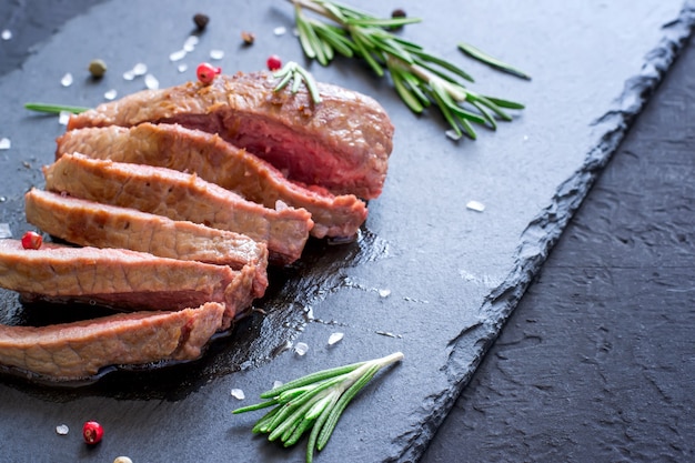 Roastbeefsteak mit Rosmarin auf Schieferbrett. Gegrilltes Fleisch Nahaufnahme, selektiver Fokus