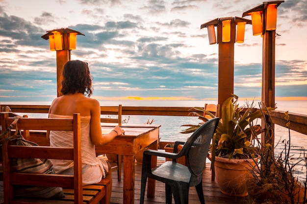 Roatán, Honduras: uma jovem mulher em um restaurante do West End na ilha de Roatan em um pôr do sol