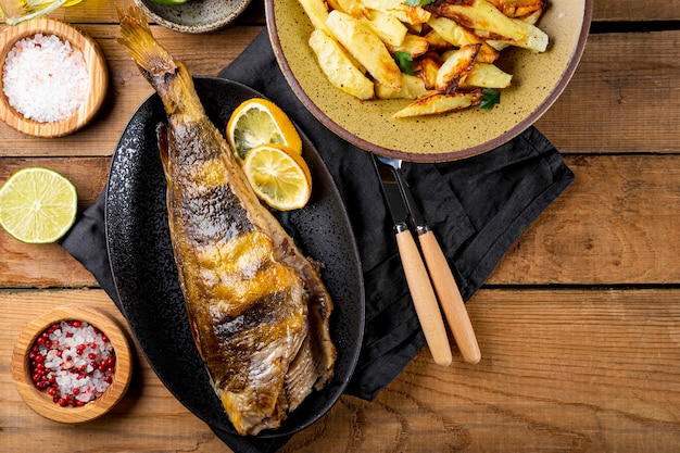 Robalo assado ou peixe lingcod com batatas na mesa de madeira