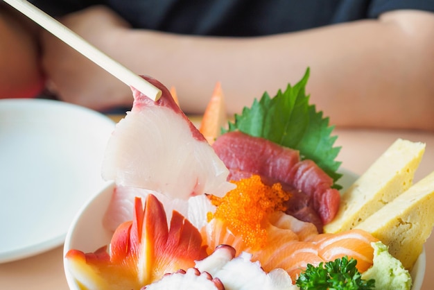 Foto robalo em pauzinhos comendo sashimi tigela de arroz chirashi don comida japonesa