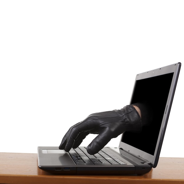 robo en Internet una mano con guantes alcanzando a través de una computadora portátil al teclado