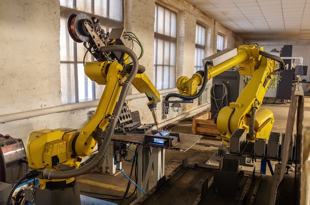 Robôs em produção. Trabalho do robô de soldagem e do robô manipulador no chão de fábrica