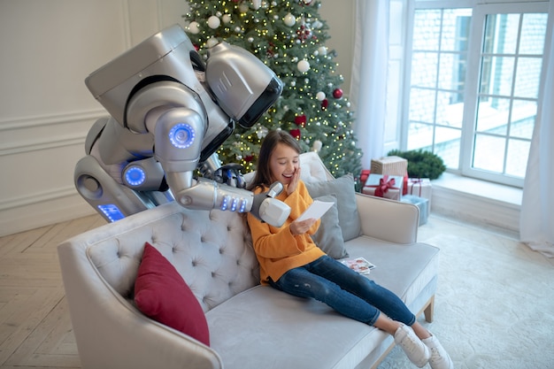 Robot y una linda chica sentada en el sofá pasando tiempo juntos