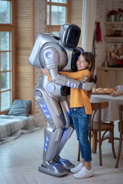 Robot y niña sintiéndose bien juntos en casa de pie en la cocina